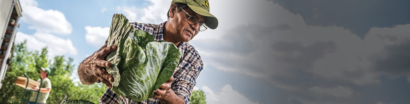 Ein Mann mit Schutzhelm an einem Arbeitsort mit John Deere Maschinen in der Nähe