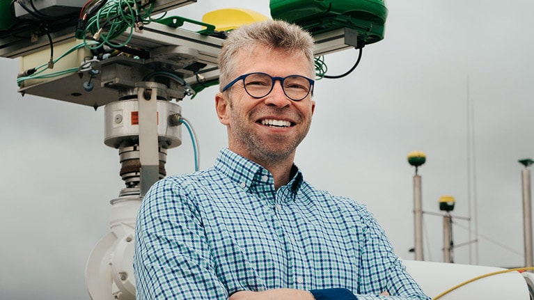 Georg Kormann, der neben einem Roboterarm steht.