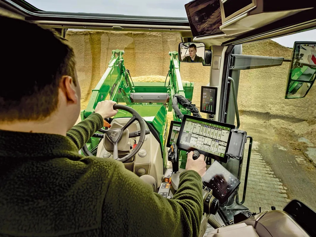 Innenansicht der Kabine des John Deere Traktors mit Bedienelementen und Frontladerbetrieb.