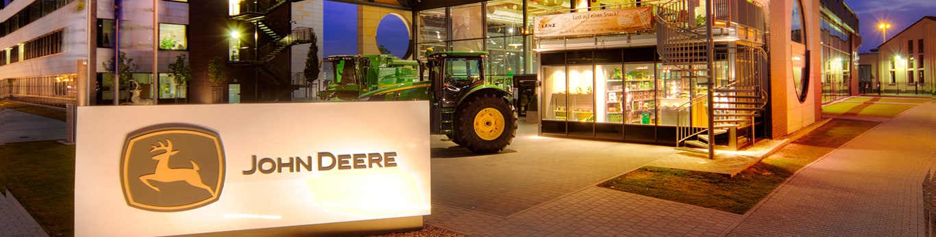 Frontaufnahme der John Deere Unternehmenszentrale mit einem Teich und Bäumen im Vordergrund