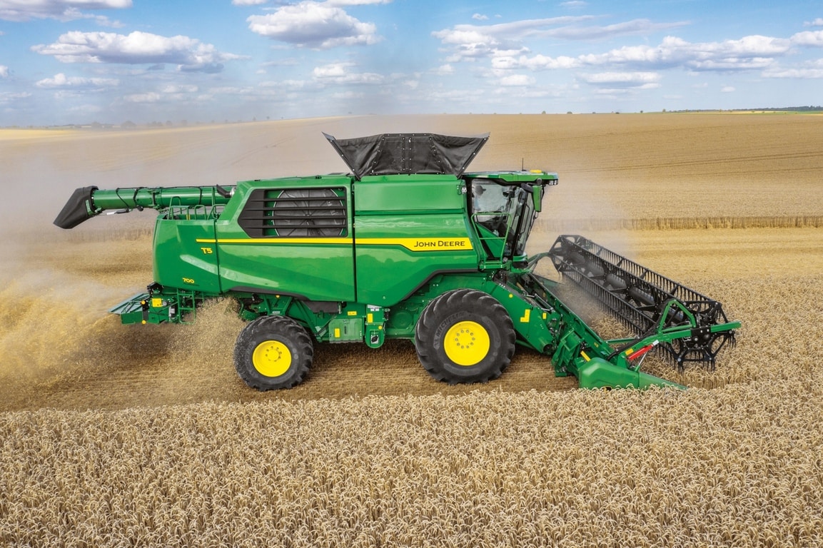 Seitenansicht eines John Deere Mähdreschers mit Schneidwerk bei der Weizenernte auf einem großen landwirtschaftlichen Feld