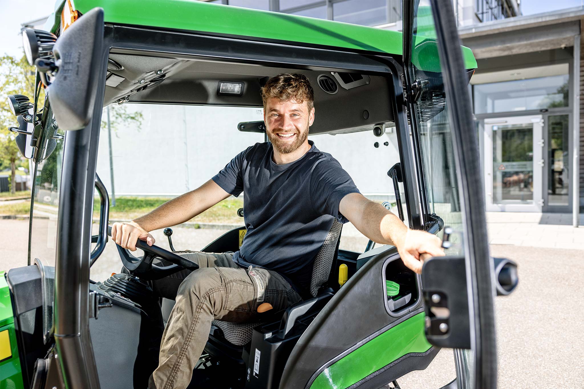 Fahrer sitzt in der Kabine eines John Deere Kompakttraktors mit offener Tür