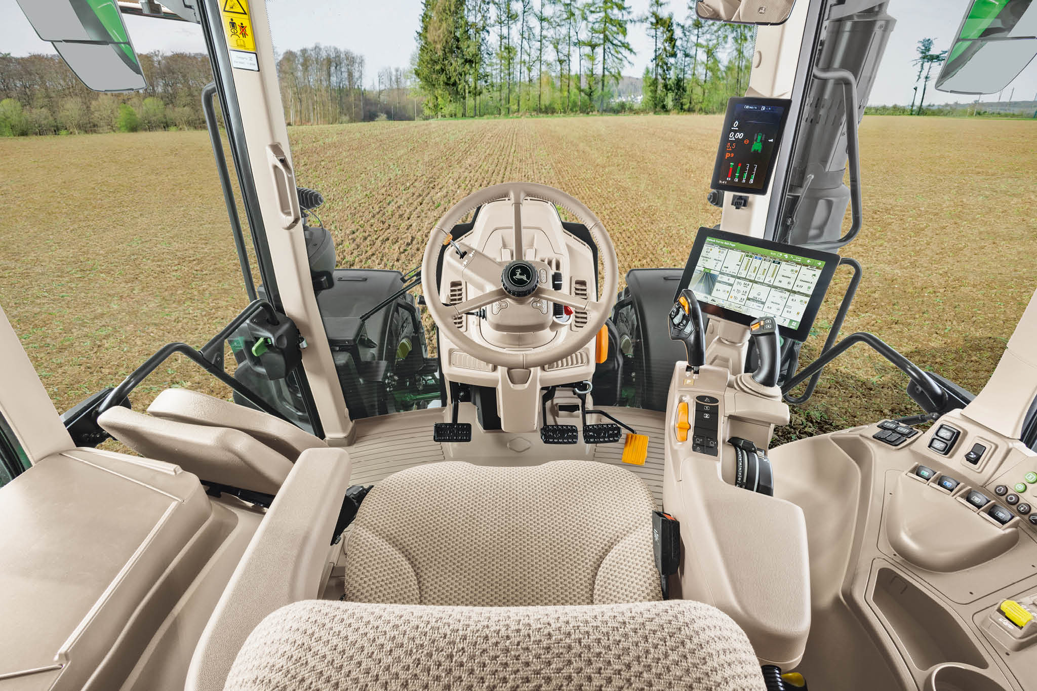 Innenübersicht einer John Deere Traktorkabine der Serie 6M mit Fahrersitz, Lenkrad und Digitalanzeigen.